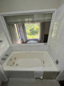 a bath tub in a bathroom with a window at Chalés da montanha in Itaipava