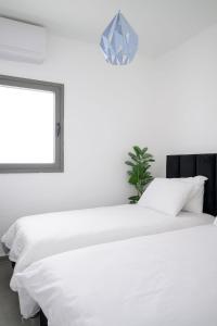 Un dormitorio blanco con dos camas y una ventana. en The most special 3-BDR on Achziv, en Nahariyya