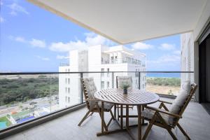 Un balcón con mesa y sillas y una gran ventana. en The most special 3-BDR on Achziv, en Nahariyya