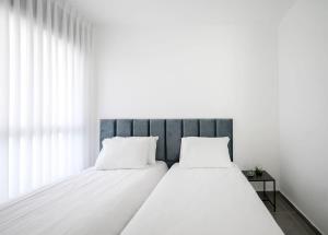 2 camas en un dormitorio con paredes blancas en The most special 3-BDR on Achziv, en Nahariyya
