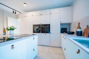 a white kitchen with white cabinets and a sink at Ferienhaus Beatus ille in Kolpinsee +35 photos