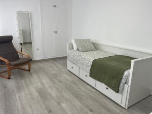 a white bedroom with a bed and a chair at Apartamento Llimera Altea in Altea