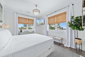 une chambre blanche avec un lit et deux fenêtres dans l'établissement Mer Soleil, à Orange Beach