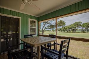 a dining room with a table and chairs and windows at 9th Tee in Caswell Beach