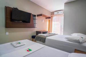 a hotel room with two beds and a flat screen tv at Pinheiro Flat Hotel in Ibiapina