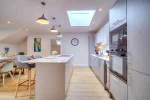 a kitchen with white cabinets and a kitchen island with a clock at Luxury Penthouse Flat Manchester in Wythenshawe +12 photos