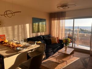 a living room with a couch and a table with food on it at Le Paradis Fort Mahon, vue mer, élégance et fraîchement rénové in Fort-Mahon-Plage