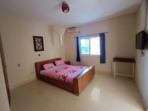 a bedroom with a bed with pink sheets and a window at Blue House in Saly Portudal