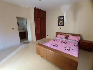 a bedroom with a large bed with pink sheets at Blue House in Saly Portudal +11 photos