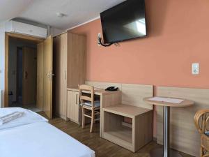 a room with a bed and a desk and a tv on the wall at Hotel garni Zur Krim in Bramsche