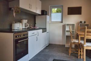 a kitchen with white cabinets and a table and a kitchen at Ferienhaus Gipfelblick im Sandsteinidyll in Rathen