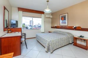 a bedroom with a bed and a desk and a sink at Hotel Suárez Campo Bom in Campo Bom