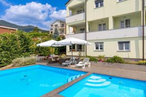 a swimming pool in front of a building at Villa Alternus-apartman Dora in Ičići