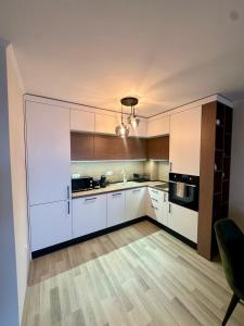 a large kitchen with white cabinets and a sink at La Veranda Apartment, complex Carpe Diem, Free Parking & Swimignpool in Balchik +27 photos