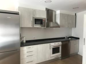 Una cocina con refrigerador de acero inoxidable y microondas. en Apartamento Turístico “El Yugo”, en Arguedas