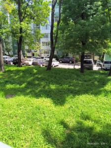 Una zona verde con árboles y coches en un estacionamiento. en Апартамент за нощувки Марго, en Burgas