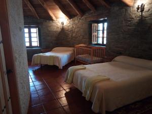 a bedroom with two beds in a stone building at El Rincón del Cuco in Tejedo de Ancares