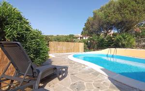 a chair sitting next to a swimming pool at Villa Blu splendida villa con piscina - Stintino Sardegna in Cuile Pazzoni