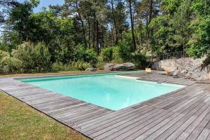 une piscine avec une terrasse en bois à côté d'une cour arrière dans l'établissement Domaine de rêve, coeur de forêt de Fontainebleau, à Le Vaudoué