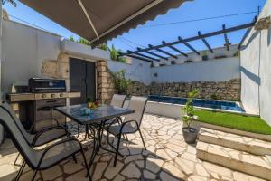 een terras met een tafel en stoelen en een zwembad bij Stone House ZEN in Grižane