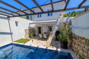een patio met een zwembad en een huis bij Stone House ZEN in Grižane