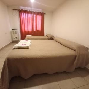 two beds in a room with a red window at Cabañas Pailalen-Planta baja in Esquel