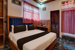 a bedroom with a large bed with red curtains at Hotel O Swastik Inn in Chinhat +21 photos