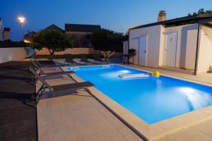 a large swimming pool with chairs and a house at Dvori dida Drage in Zaton