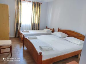 two beds in a room with a window at Spacious-Central Apartment in Himare