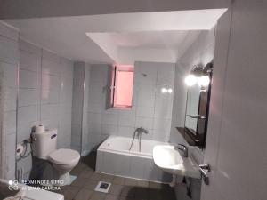 a bathroom with a toilet and a tub and a sink at Spacious-Central Apartment in Himare +6 photos