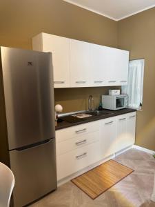 a kitchen with white cabinets and a stainless steel refrigerator at HOUSE on sunday LUNA in Crotone