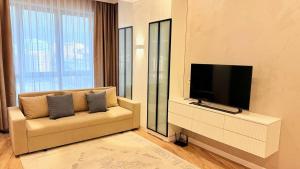een woonkamer met een bank en een flatscreen-tv bij Seven Hills in Alma-Ata