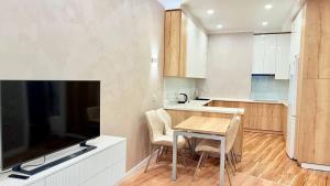 een keuken met een tafel en een tv in een kamer bij Seven Hills in Alma-Ata