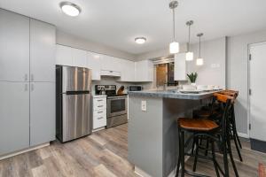 a kitchen with white cabinets and a counter with bar stools at Modern & Chic Condo in the Heart of Old Town in Fort Collins