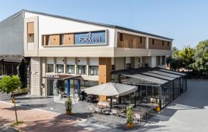 a front view of a hotel with tables and umbrellas at Fora Inn Lara in Antalya