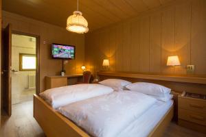 a bedroom with a large bed with a television in it at Pensione Erica in Colfosco