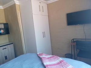 a bedroom with a bed and a tv and white cabinets at Comfy at Sosha in Soshanguve