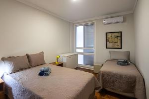 a bedroom with two beds and a window at Gonzaga Beach Vibes: Pé na Areia com 2 quartos in Santos +54 photos