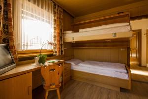a small room with two bunk beds and a desk at Pensione Erica in Colfosco