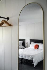 a mirror in a bedroom with a bed with a orange pillow at Lumberjill Lodge 13 Double Queen Room in Balsam Lake