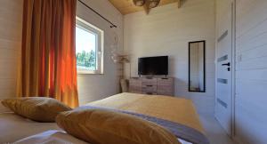 una camera da letto con un letto e una televisione su una cassettiera di Domki La Luz a Ustronie Morskie