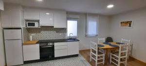 a kitchen with white cabinets and a table and a table and chairs at Casa Saballa in O Grove