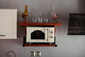 a microwave on a wall with a shelf with wine glasses at Casa Anastacia Sykia in Sikia