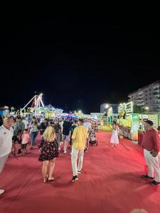 a group of people walking around a carnival at night at aldo apartments in Shëngjin