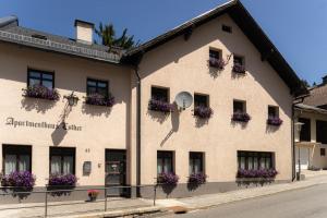 budynek z skrzyniami kwiatów i zegarem w obiekcie Apartmenthaus Esther w mieście Ramingstein