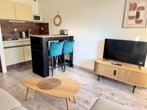 a living room with a tv and a table at Le Plein Soleil- Studio Piscine et Plage a 100m- La Grande Motte- LaConciergerieByNina in La Grande-Motte +10 photos