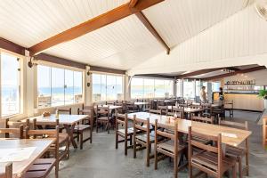 a dining room with tables and chairs and windows at Flat 208-A Vista Mar com Piscina in Cabo Frio