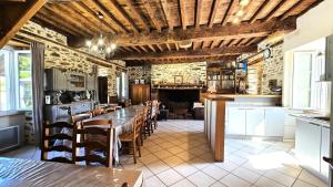 a dining room with a long table and a kitchen at Gîte de France "les volets bleus" 3 épis - Gîte de France 12 personnes MAE-9484 in Espartignac