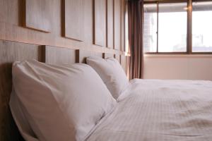 a bed with white sheets and pillows next to a window at KIWI-Taichung Station Branch 1 in Taichung