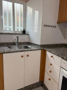 a white kitchen with a sink and a window at casa en Cedeira in Cedeira